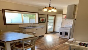 Una cocina con una mesa y sillas de madera, un lavamanos, armarios y una estufa.