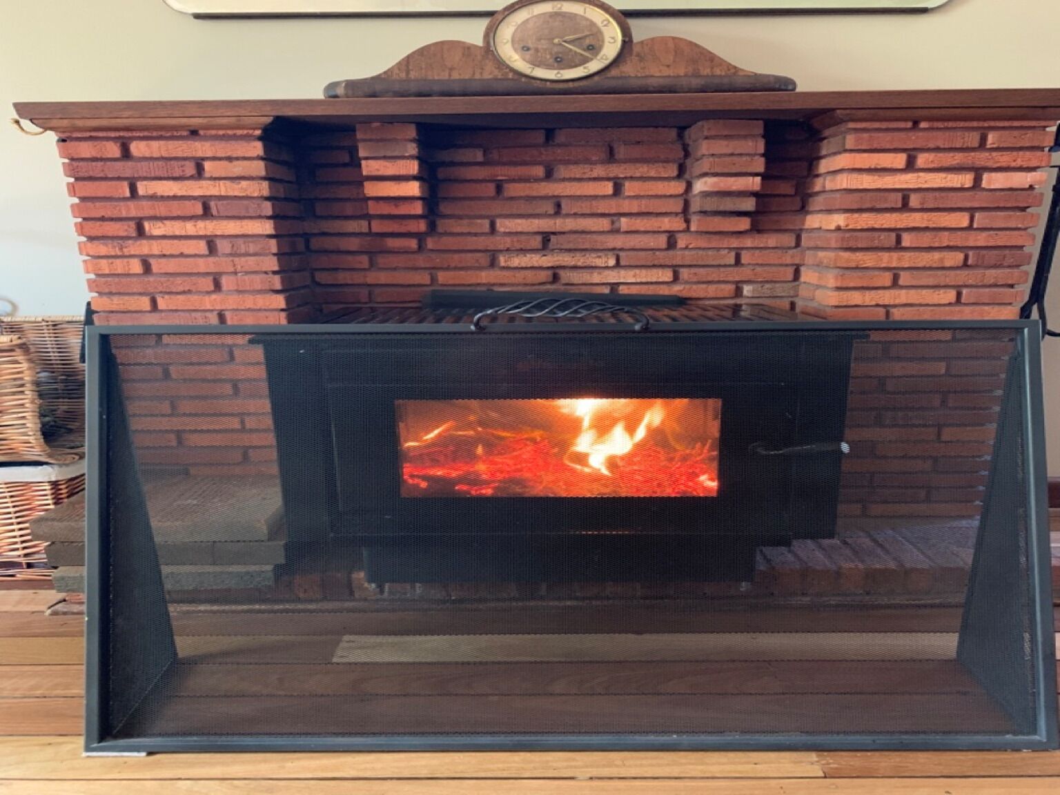 Una chimenea con frente de ladrillo y protección de vidrio.