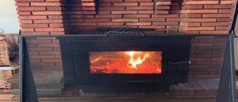 Una chimenea con frente de ladrillo y protección de vidrio.