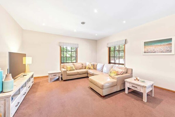 A living room with a sectional sofa, a coffee table, and a TV on a stand.