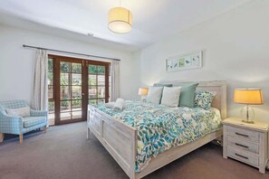 A bedroom with a bed, bedside tables, a chair, and a window with curtains.