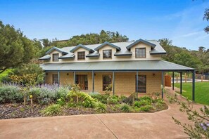 A two-story house with a covered porch, a well-maintained garden, and a clear sky.