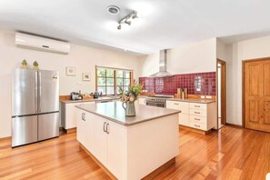 A modern kitchen with a central island, stainless steel appliances, and a red-tiled backsplash.