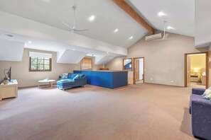 Ein geräumiges Loft mit hoher Decke, einem blauen Sofa, einem kleinen Tisch und einer integrierten Schreibtischzeile.