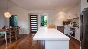 Een moderne keuken met een centraal eiland, roestvrijstalen apparatuur en een eethoek met houten stoelen.