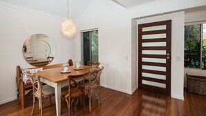Een eetruimte met een houten tafel, stoelen, een ronde spiegel en een hanglamp.
