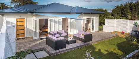 A modern house with a covered patio, outdoor furniture, and a well-maintained lawn.