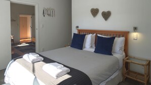 Une chambre d’hôtel avec un grand lit, deux décorations murales en forme de cœur et une petite table d’appoint en bois.