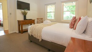 Une chambre à coucher avec un lit, un bureau en bois, une télévision et des fenêtres.