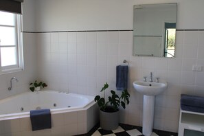 A bathroom with a bathtub, sink, and potted plants.