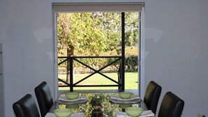 Une table à manger avec six chaises, mise pour un repas, avec des bols verts et des serviettes blanches.