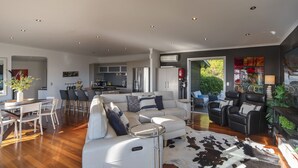 Una sala de estar moderna con sofá, sillas, una mesa de comedor y una cocina al fondo.