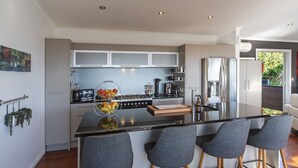 Una cocina moderna con una isla central, taburetes de bar y un refrigerador.