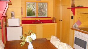 A compact kitchen with wooden cabinets, a red countertop, a small refrigerator, and a white stove. - Quaint character cottage on working farmlet, Running Sheep & Beef. (Upper Moutere)