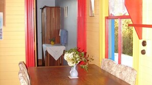 A dining area with a wooden table, a vase with flowers, and a bench. - Quaint character cottage on working farmlet, Running Sheep & Beef. (Upper Moutere)