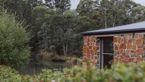 A stone building with a door and window, surrounded by greenery and trees. - Naivasha Cottage with antique outdoor bath (REEDY MARSH)