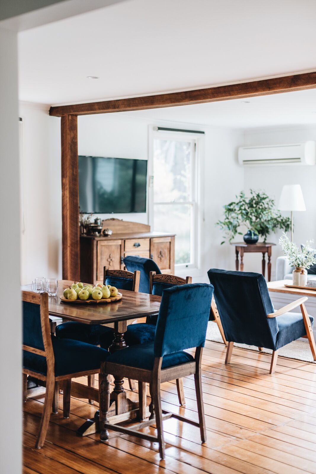 A dining area with a wooden table, blue upholstered chairs, and a wooden floor.