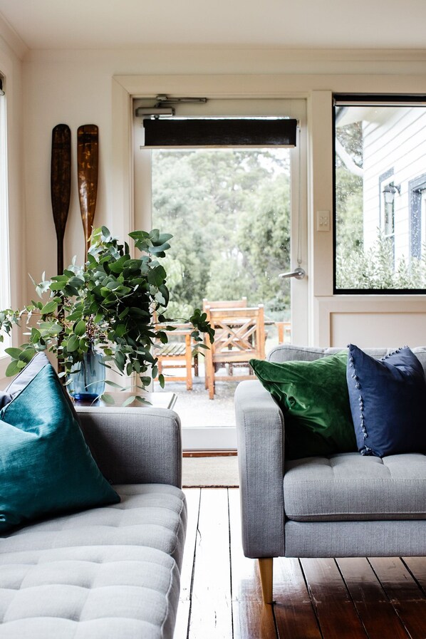Une pièce avec deux canapés gris, une plante en pot et une table en bois.