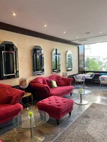 Un área de estar moderna con sofás tapizados en rojo, mesas de vidrio y vistas al exterior.