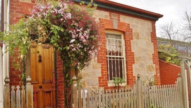 Un edificio de ladrillo con puerta de madera y una ventana pequeña.