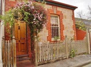 A brick building with a wooden door and a small window. - Chapel Cottage 2 bedroom (North Adelaide)