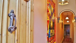 Un pasillo con una puerta de madera, un tapiz de colores y un arco de entrada a otra habitación.