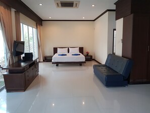 A hotel room with a bed, a sofa, a TV, and a desk.