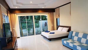 A modern hotel room with a large bed, a sofa, a TV, and a sliding glass door leading to a balcony. - Beautiful detached 5 bedroom, 4 bathroom Private Pool Villa, Kathu Phuket (Kathu)