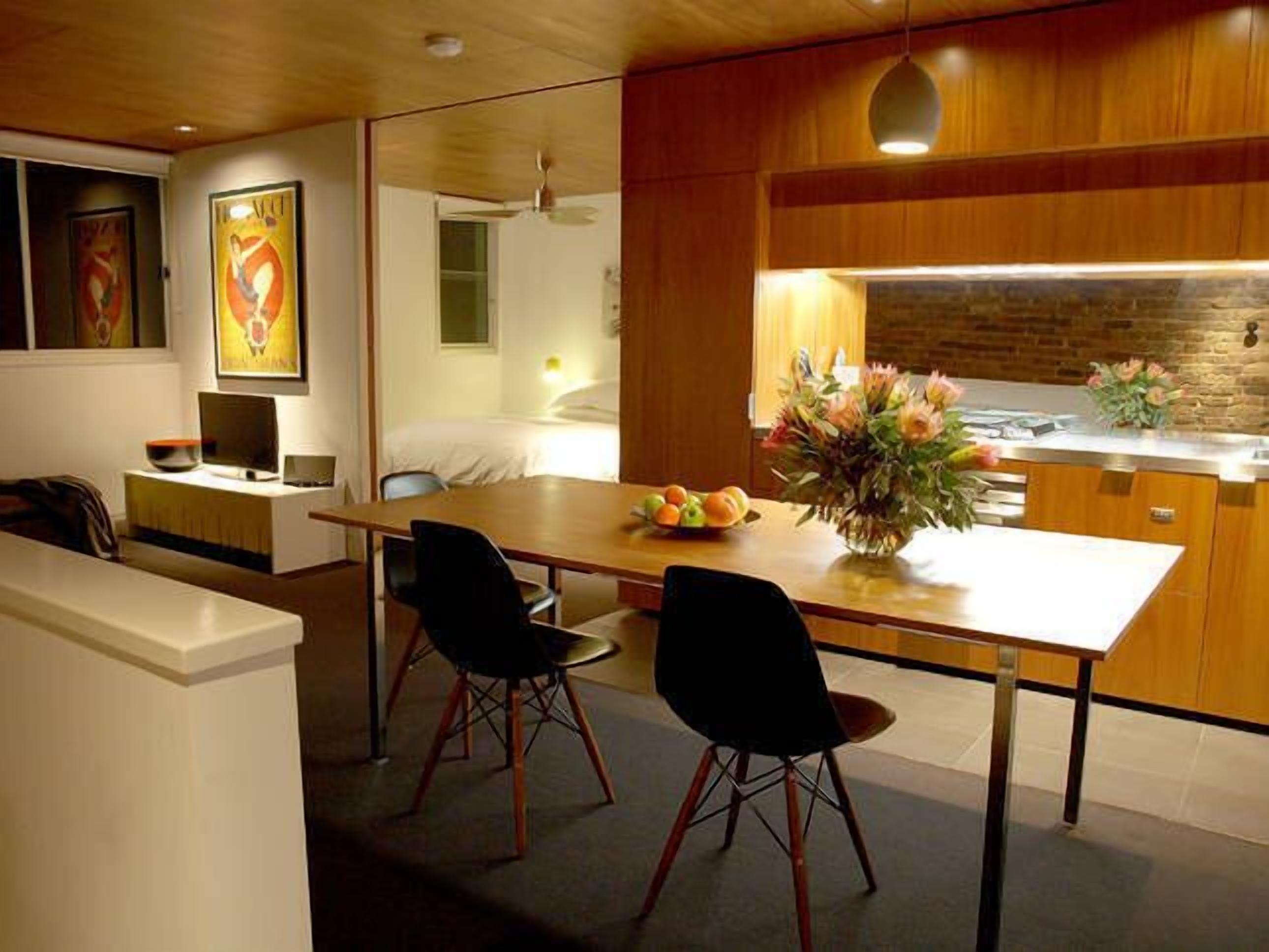 Una cocina moderna con encimera de madera, dos sillas negras y un jarrón con flores.