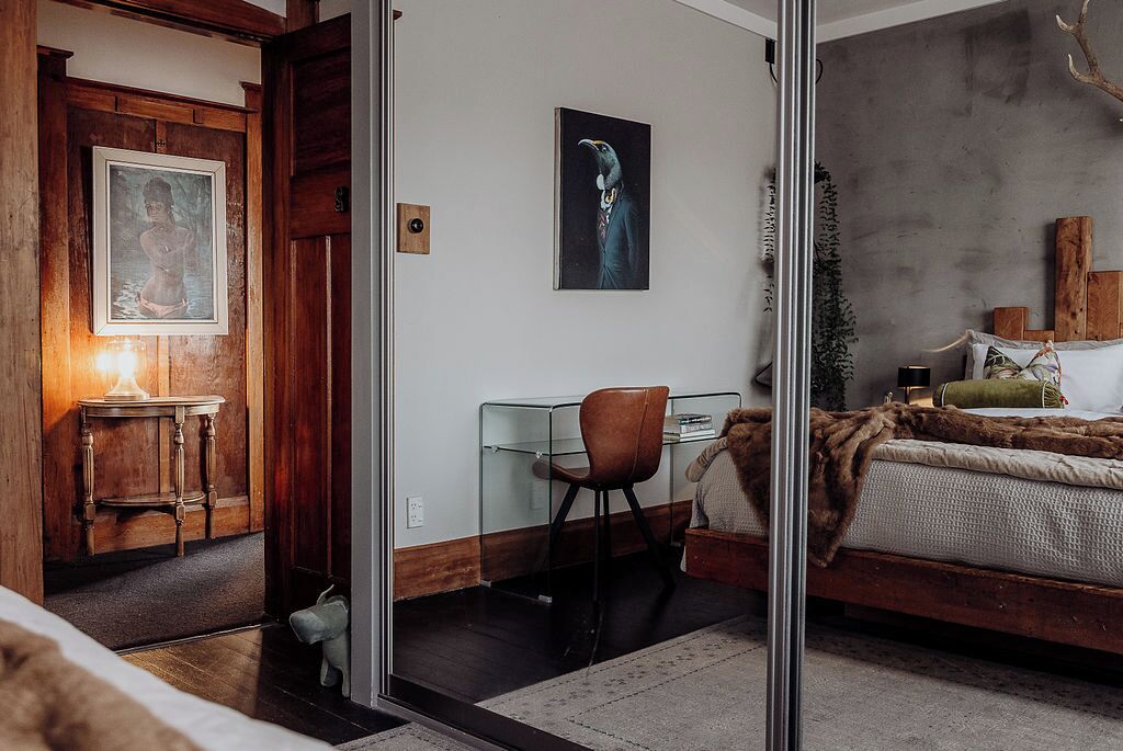 Ein Schlafzimmer mit Bett, Schreibtisch, Stuhl und einer Glastrennwand.