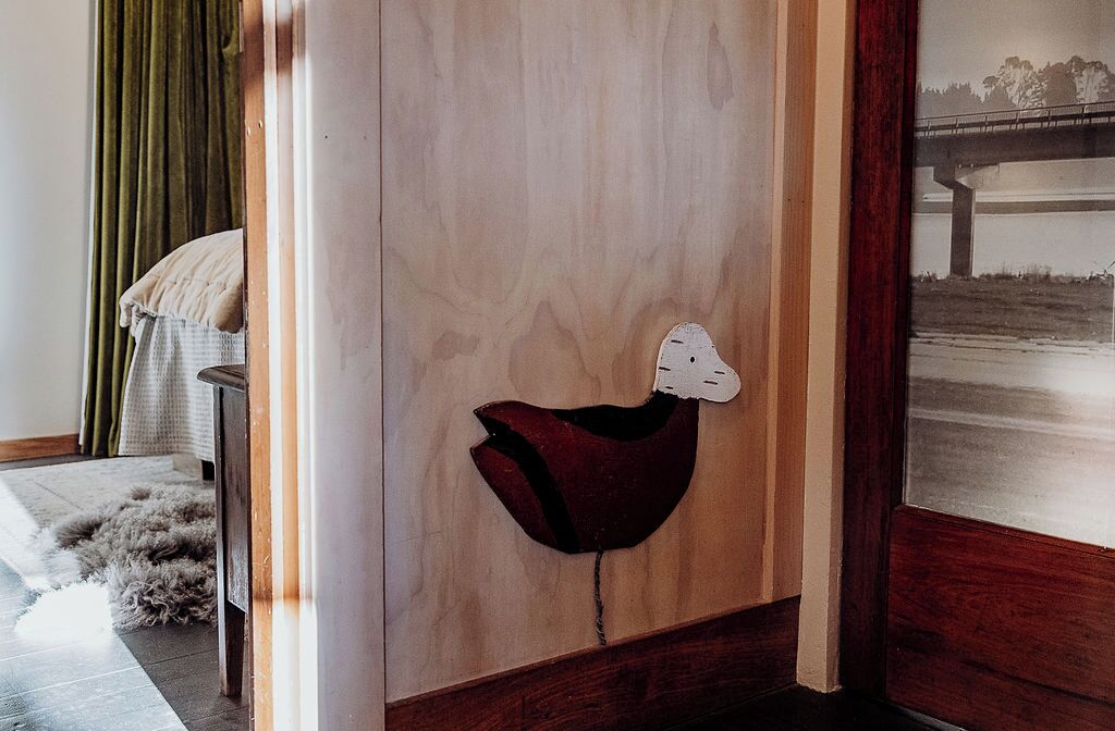 A room with a wooden door, a red chair, a green curtain, and a view of a bridge.