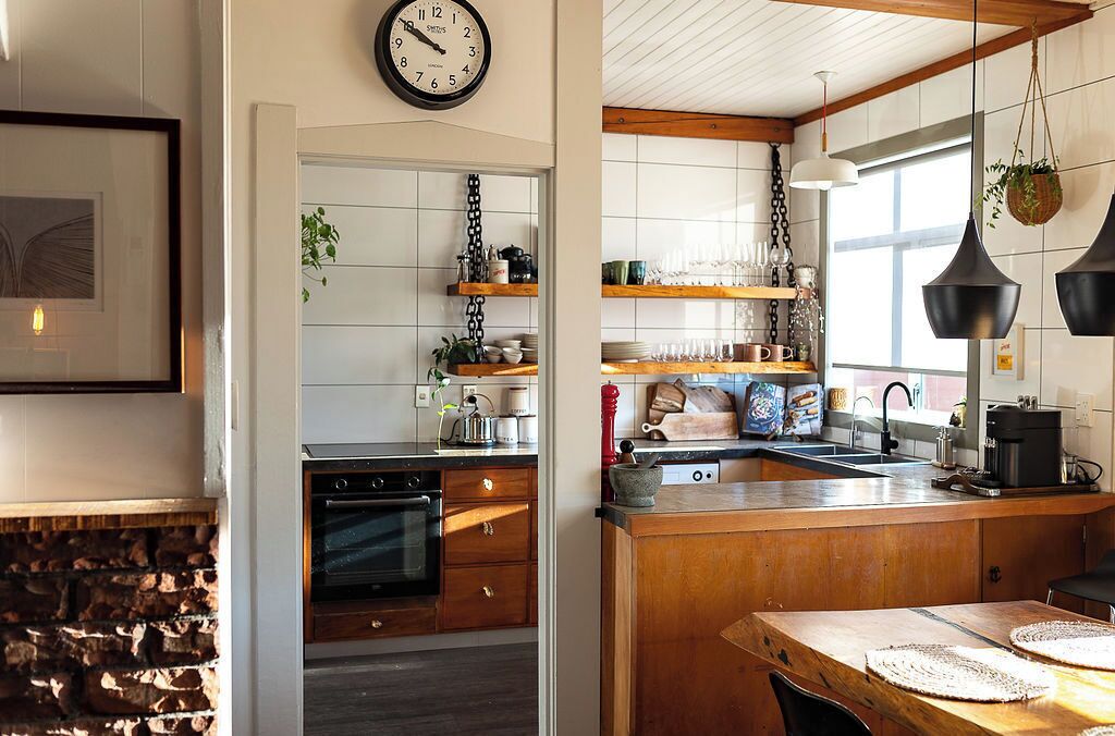 A kitchen with wooden cabinets, a built-in oven, a sink, and hanging pendant lights.