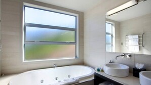 Une salle de bain moderne avec une baignoire sur pieds, deux lavabos et une grande fenêtre offrant une vue sur l’extérieur.
