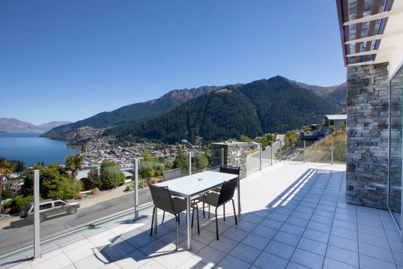 Ein Balkon mit Tisch und Stühlen mit Blick auf eine Stadt und Berge.