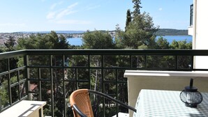 A balcony with a view of a lake, trees, and distant buildings. - Comfort One-Bedroom Apartment With Balcony and Swimming Pool (Trogir)