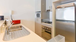 Una cucina compatta con lavandino, microonde, fornello e frigorifero.