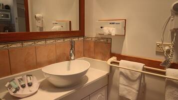 Un baño con un lavabo blanco, un espejo, un toallero y un dispensador de pañuelos.