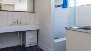 Un baño con un lavabo blanco, dos grifos, un espejo y una toalla azul colgada en la pared.