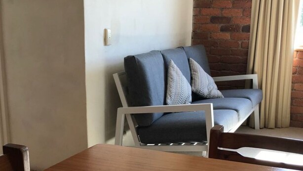 Una sala de estar moderna con un sofá gris, una mesa de madera y una pared de ladrillo.