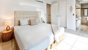 Une chambre spacieuse avec un grand lit, des lampes de chevet, un ventilateur de plafond et une vue sur la salle de bain.