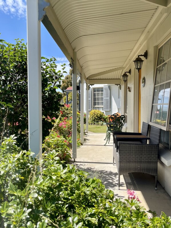 A covered outdoor area with a bench and potted plants.