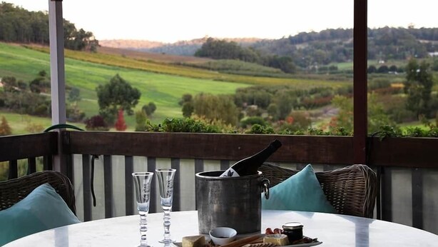 A table with a metal pot, glasses, and food items on a terrace with a view of a green landscape. - Bickley Valley Cottage (Bickley)