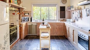 A compact kitchen with a central island, a microwave, a stove, and a dishwasher. - Bickley Valley Cottage (Bickley)
