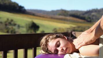 Guests can unwind with a soothing massage on a plush cushion, surrounded by serene natural beauty.