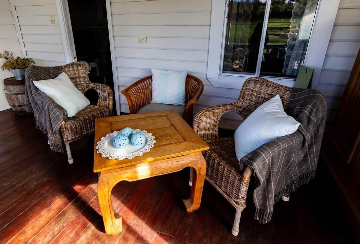 Un espacio al aire libre acogedor con mobiliario de mimbre y una mesa de madera.