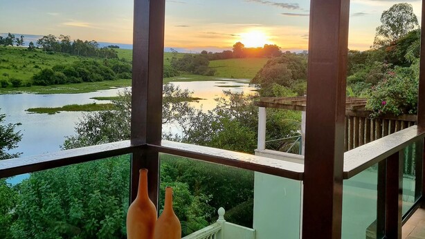 Un balcón con vista a la puesta de sol sobre un río y follaje.