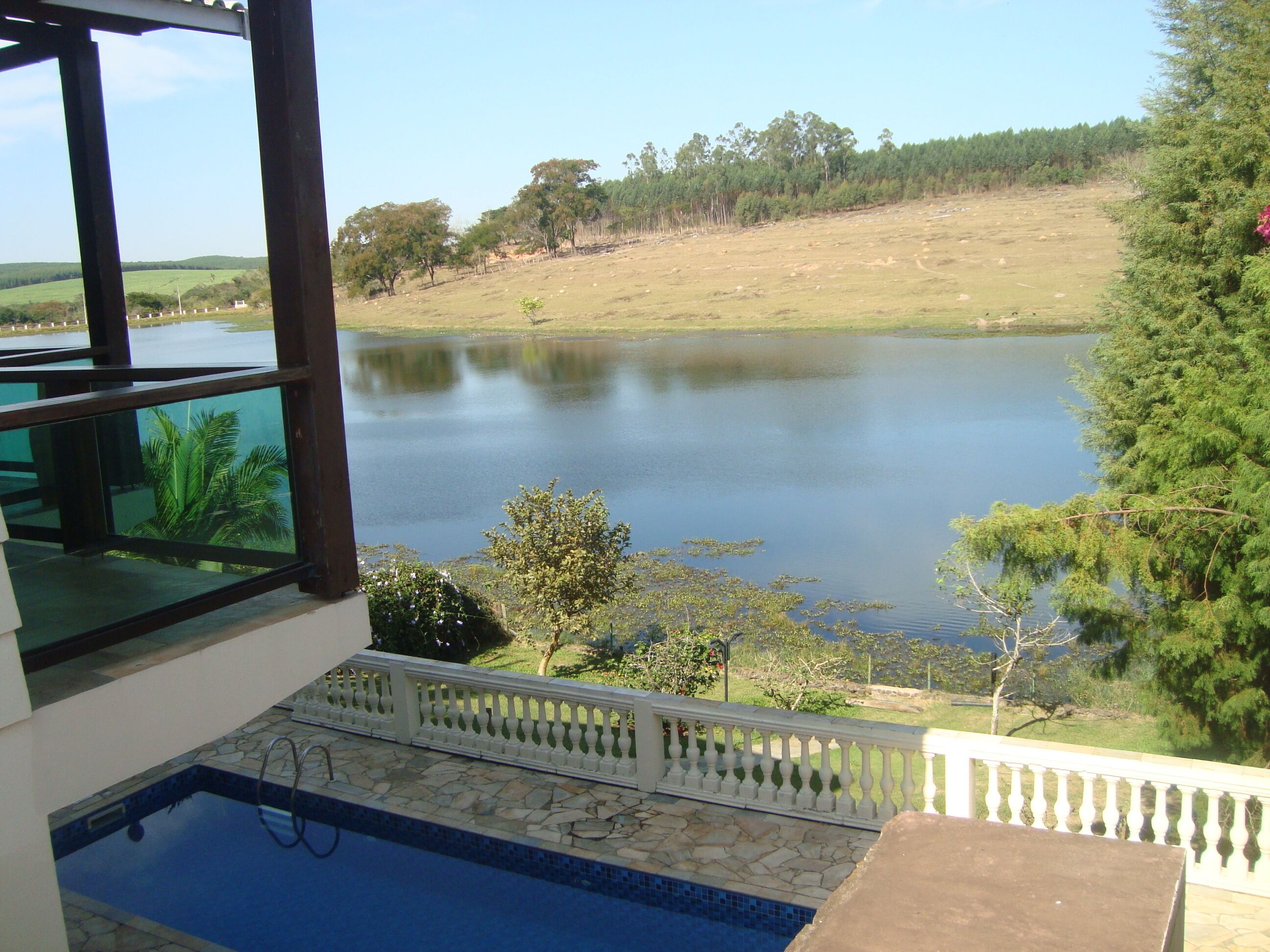 Ein Pool mit Steinrand, Blick auf einen See und eine Holzterrasse.