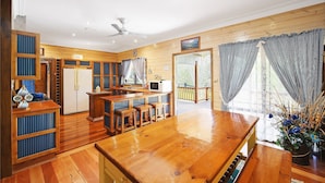 Una cocina amplia con armarios de madera, un comedor con una gran mesa de madera y vistas al exterior a través de ventanas grandes.
