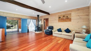 Amplia sala de estar con piso de madera, chimenea, sofá y ventilador de techo.