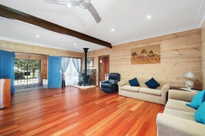 A spacious living room with wooden flooring, a fireplace, a sofa, and a ceiling fan.